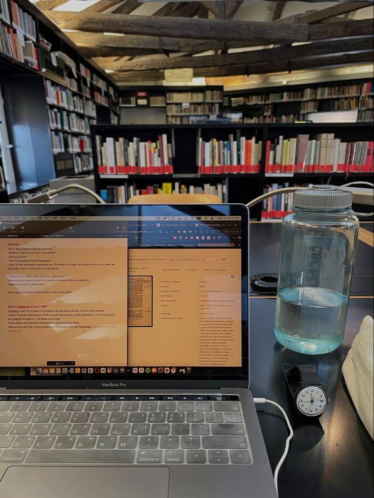 an open laptop computer sitting on top of a table in front of a bookshelf