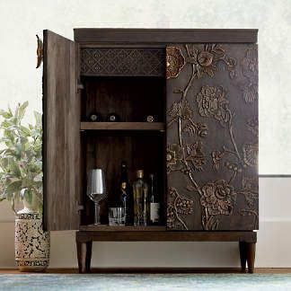 a wooden cabinet sitting on top of a rug next to a vase and potted plant