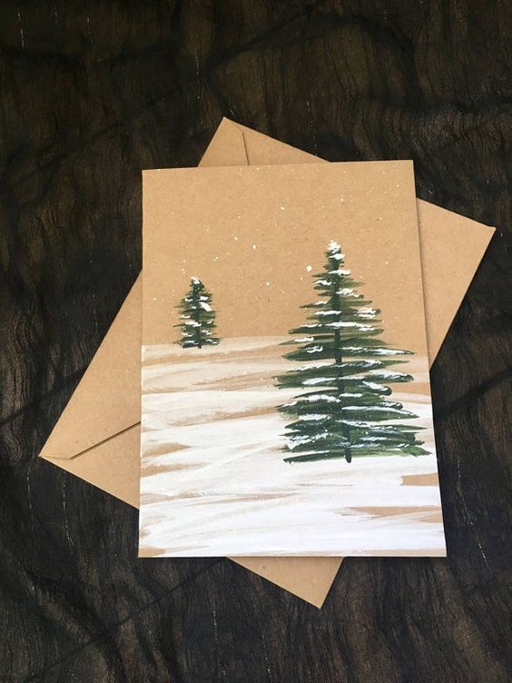 two cards with trees painted on them sitting on a table next to some brown paper