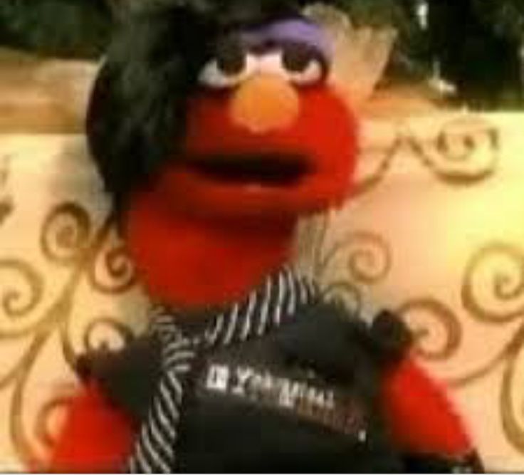 the muppet is wearing a black vest and standing in front of a christmas tree