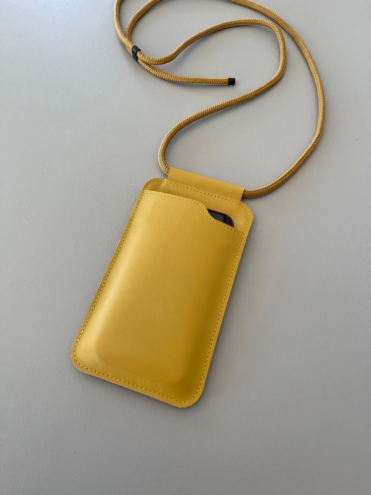 a yellow cell phone case with a cord attached to it on a white table top