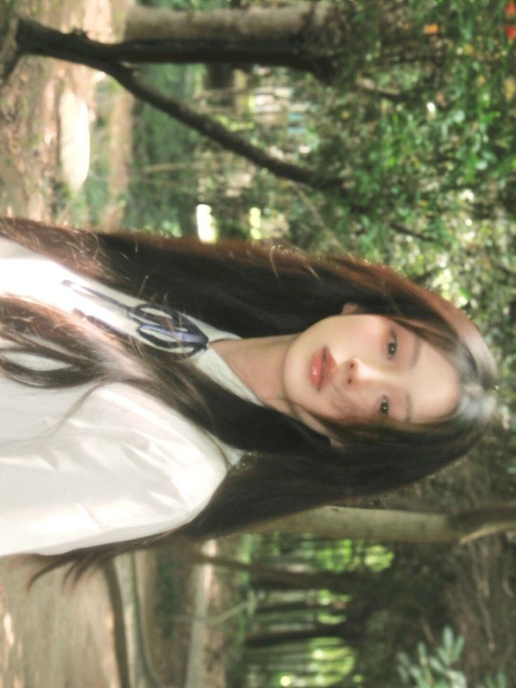 a woman with long hair standing in the woods