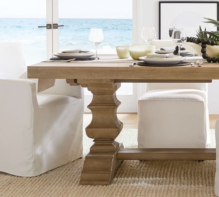 a dining room table with white chairs and an ocean view