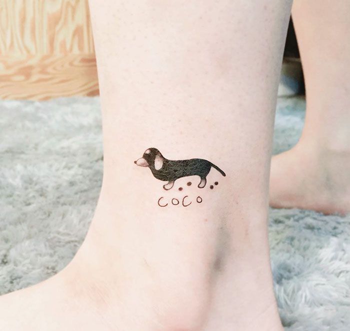 a small black and white dog tattoo on the ankle