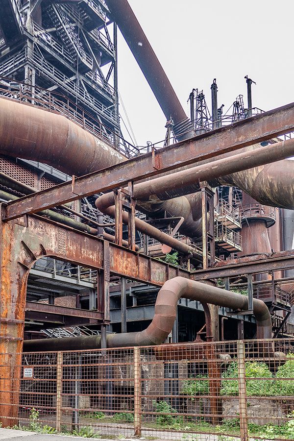 an old factory building with pipes and piping from it's roof to the ground