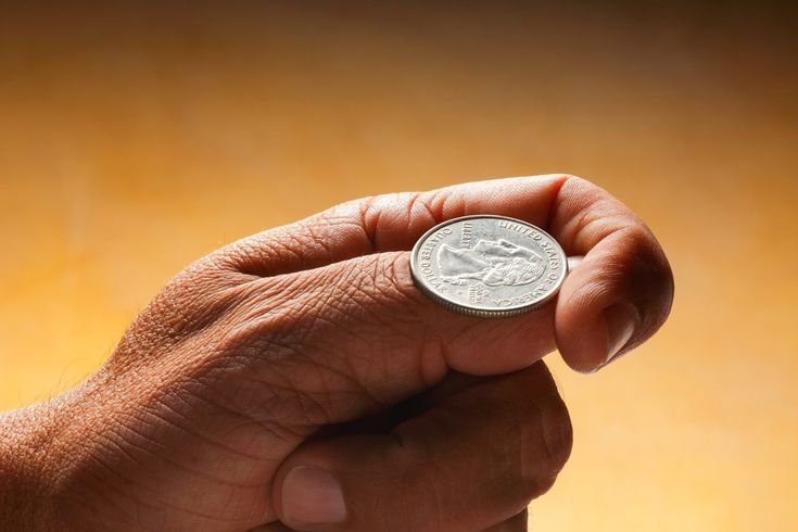 a person holding a coin in their left hand with both hands on the other side