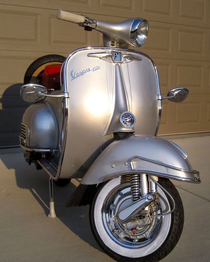 a silver scooter parked in front of a garage