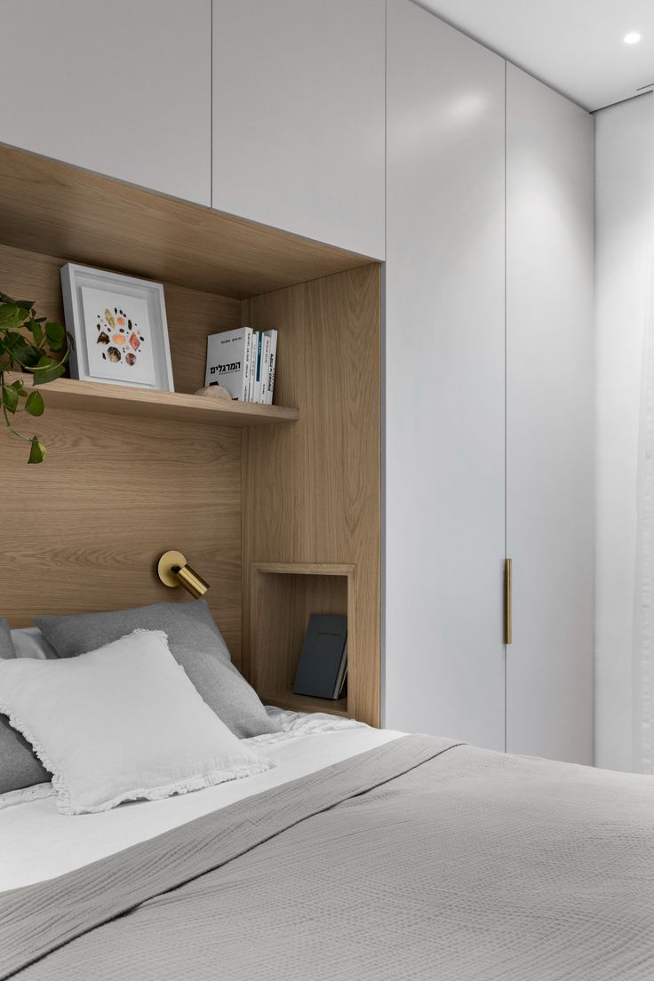 a bed with white sheets and pillows in a room that has wooden shelves on the wall