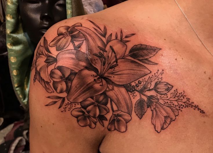 a woman's shoulder with flowers and leaves on it