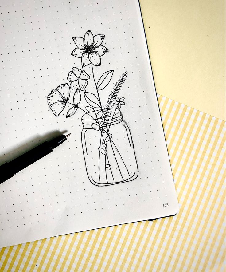 a drawing of flowers in a mason jar on top of a notepad next to a pen