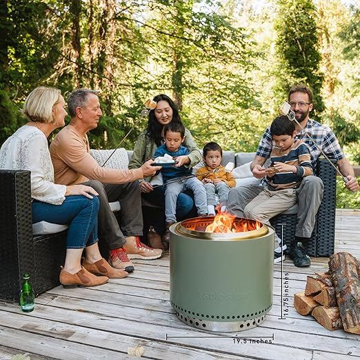 a group of people sitting around a fire pit on a wooden deck in the woods