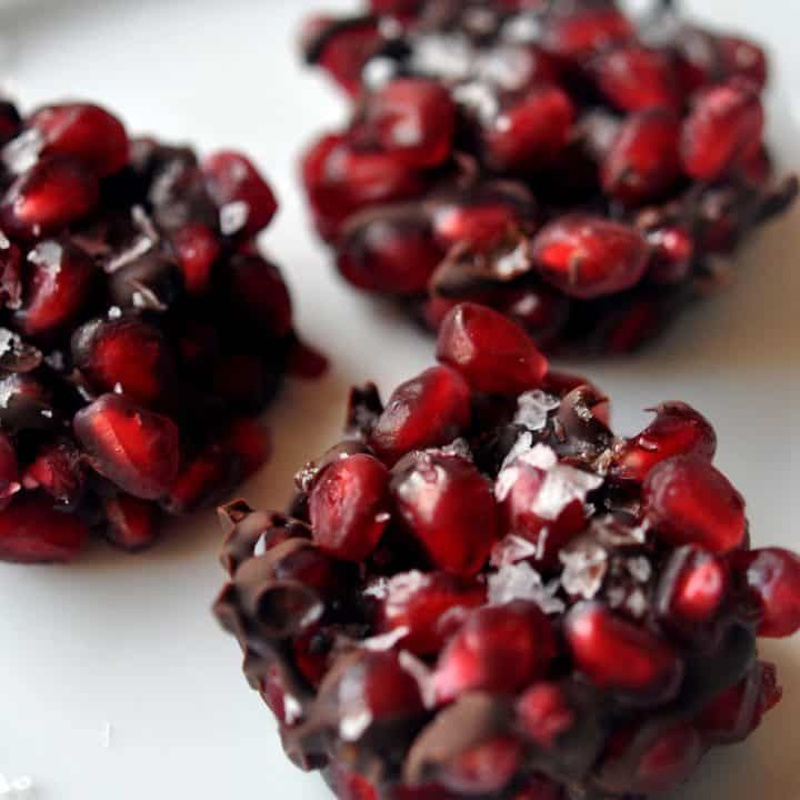 three pomegranates sitting on top of a white plate