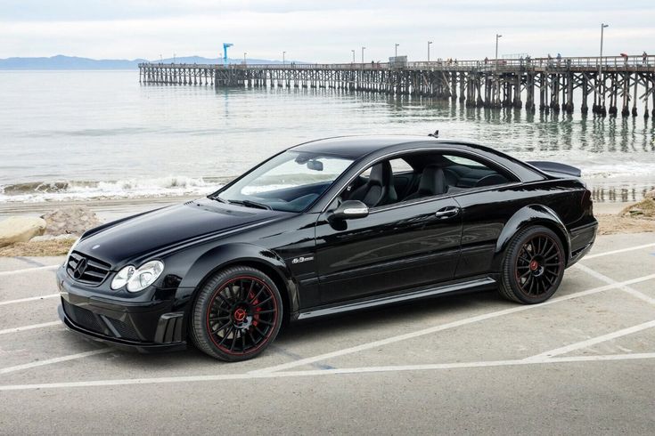 a black car parked in a parking lot next to the ocean