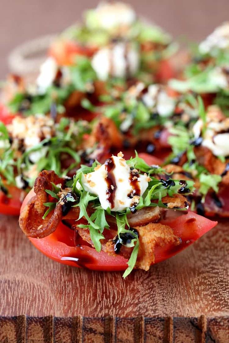 a wooden cutting board topped with sliced tomatoes and other food items on top of it