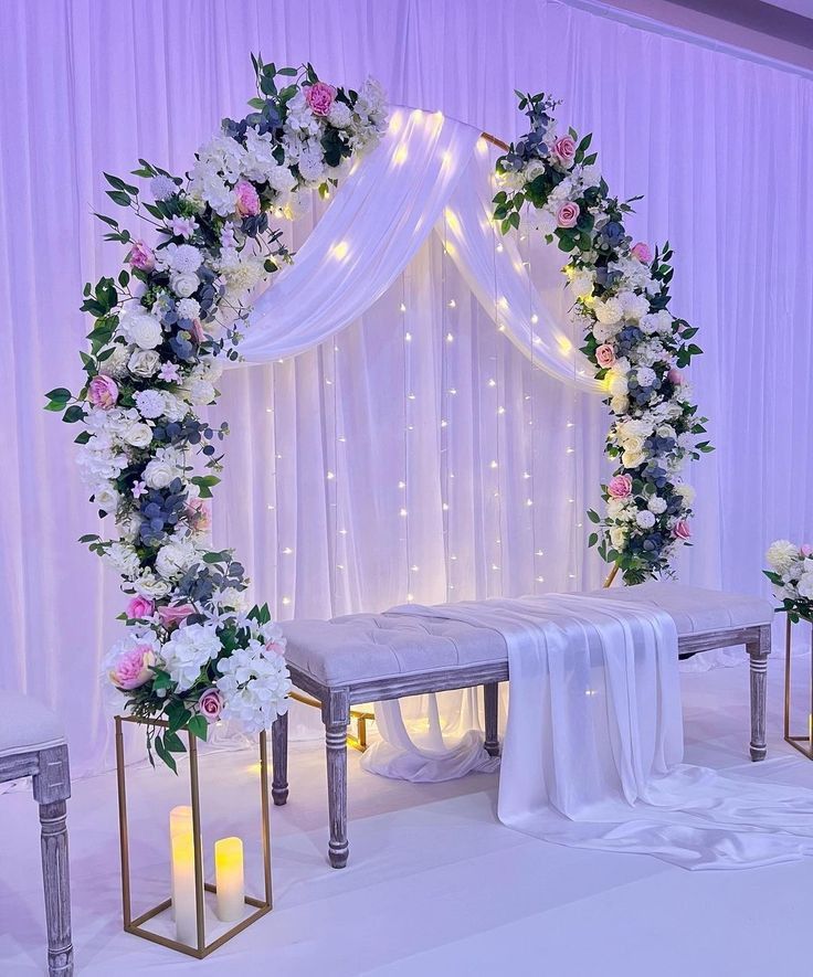 a wedding ceremony setup with white and pink flowers on the altar, candles and drapes