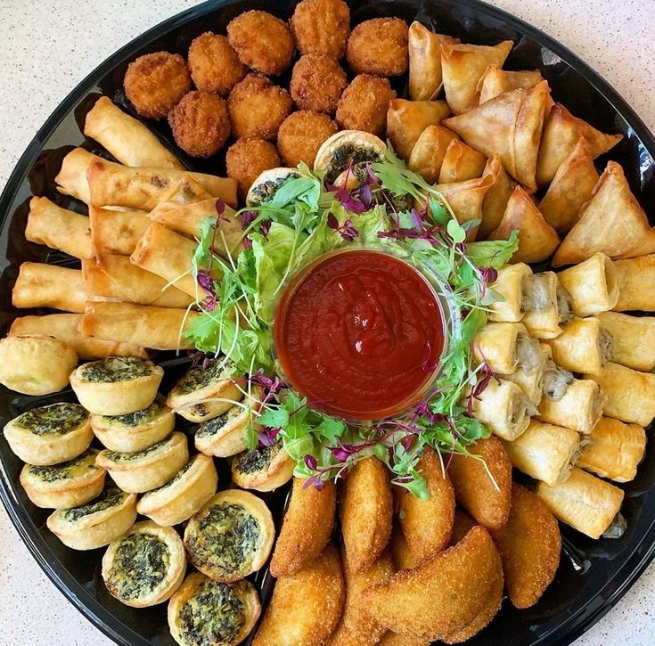 a platter filled with different types of appetizers and dipping sauce on top