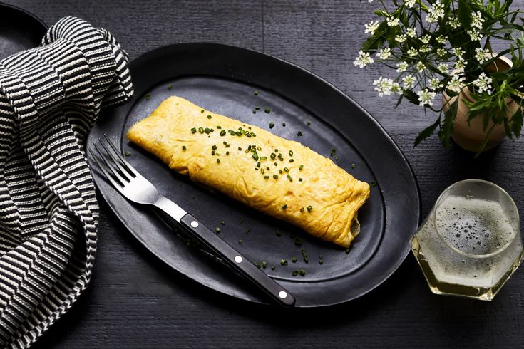 an omelet is on a black plate with a fork