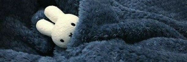 a teddy bear is peeking out from behind a blue fluffy blanket that has been folded over