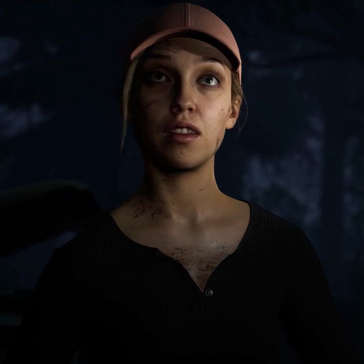 a young woman in a baseball cap stares at the camera while standing against a dark background