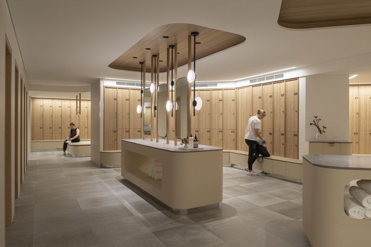 a man is standing in the middle of a room with wooden lockers and sinks