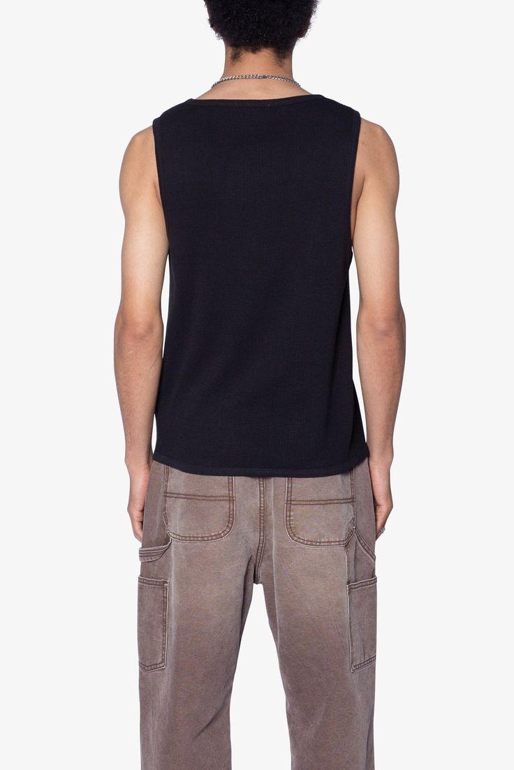 the Waffle Knit Tank is a 100% cotton tank is perfect as a base layer or worn alone. the tank features taping at the neck and arm openings, a flat hem, and is constructed in a ribbed material. details flat hem 100% ribbed cotton fabric Model is 6’0, 140 lbs and wears a size medium Black Sleeveless Top With Ribbed Neckline, Casual Ribbed Tank Top For Streetwear, Stretch Ribbed Tank Top For Streetwear, Black Cotton Muscle Tee For Layering, Casual Ribbed Vest With Tank Straps, Black Cotton Muscle Tee For Everyday, Casual Tank Strap Tops For Streetwear, Casual Streetwear Tops With Tank Straps, Cotton Ribbed Sweater Vest For Layering