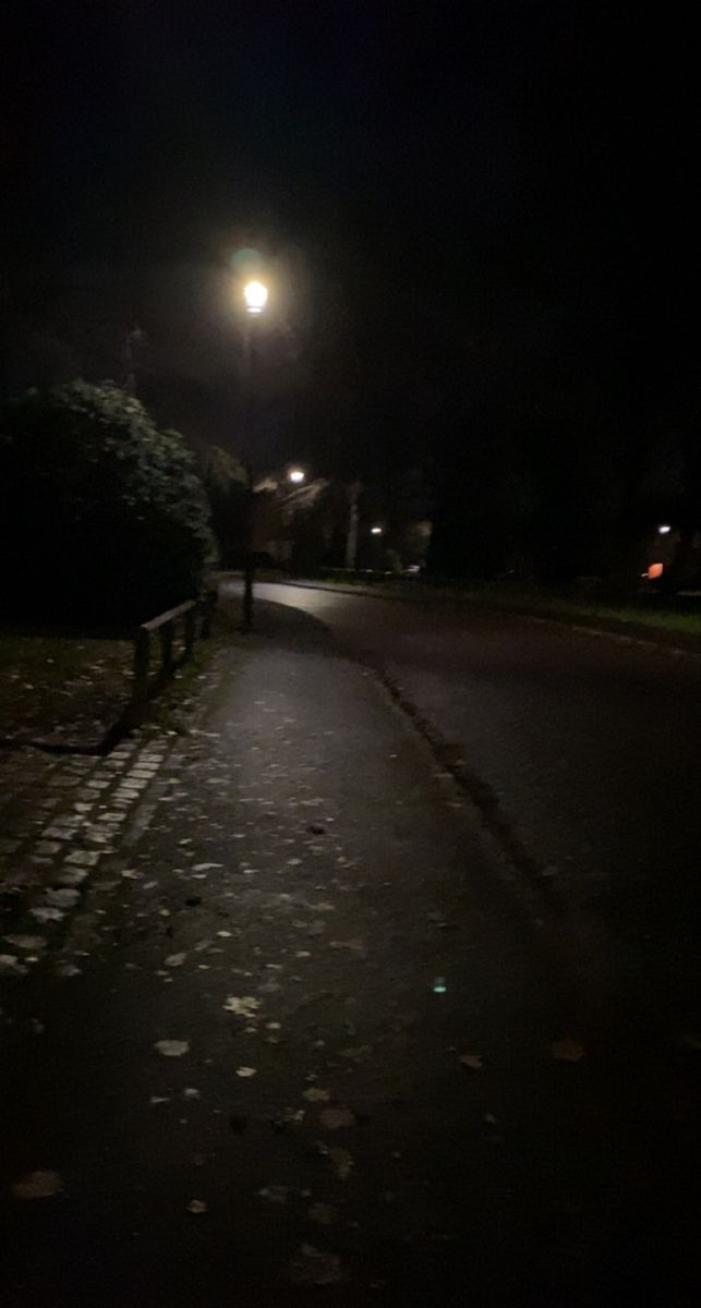 a bench sitting on the side of a road at night