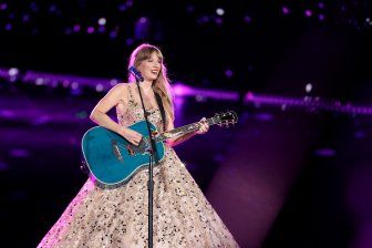 a woman in a dress holding a blue guitar and singing into a microphone on stage