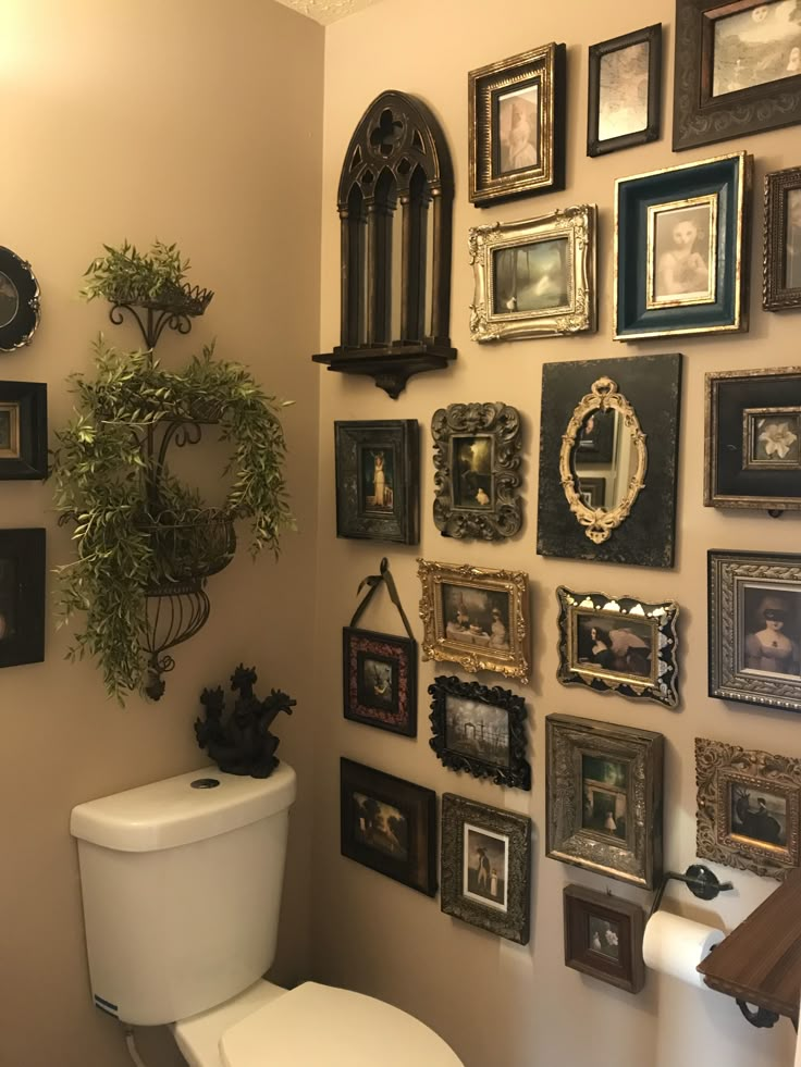 there is a toilet in the bathroom with many framed pictures on the wall above it