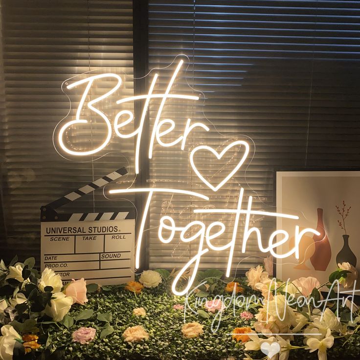 a neon sign that says better together in front of flowers