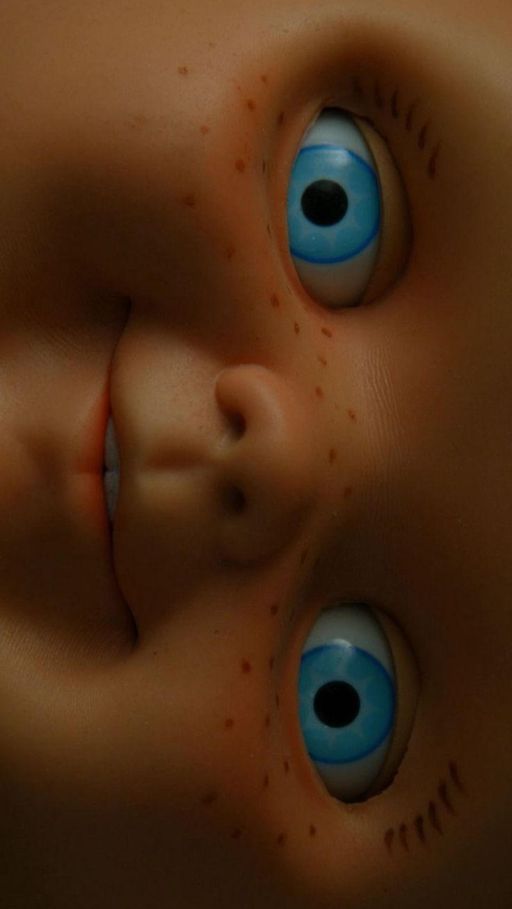 an image of a creepy doll's face with blue eyes and blood on it