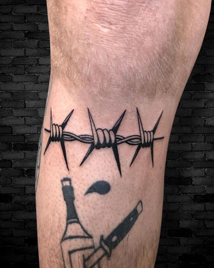 a man's leg with barbed wire and wine bottle on it