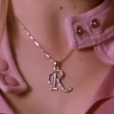 a close up of a person wearing a pink shirt with a silver necklace on their neck