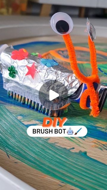 an orange and silver brush sitting on top of a wooden table covered in tin foil