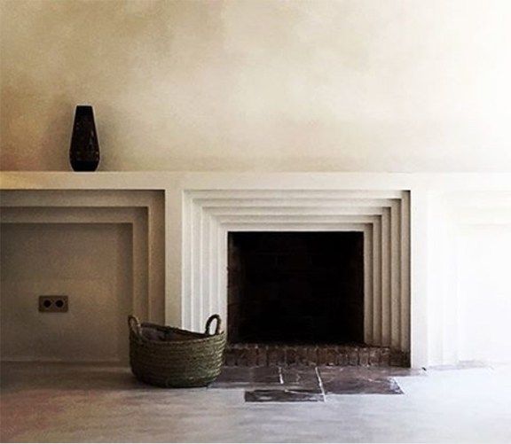 an empty room with a basket on the floor in front of a fire place and fireplace