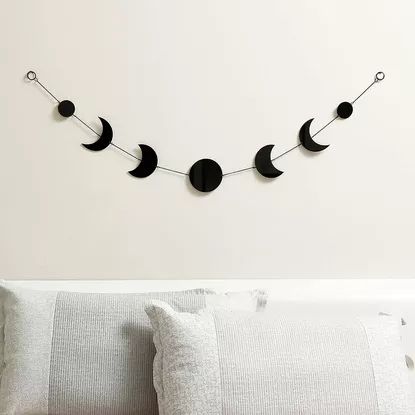 a white bed topped with pillows next to a wall mounted crescent moon and star string