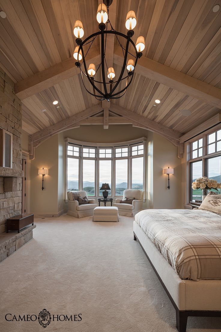 a bedroom with a large bed and two lamps hanging from it's ceiling beams