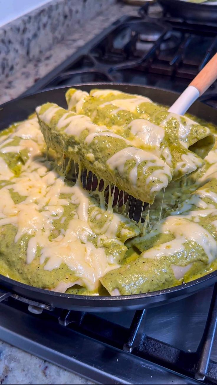 a skillet filled with green sauce and tortilla shells on top of a stove