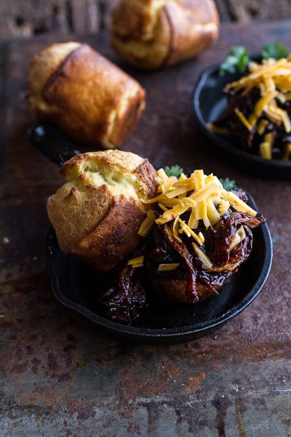 two black plates topped with pastries covered in cheese and chili sauce next to bread rolls