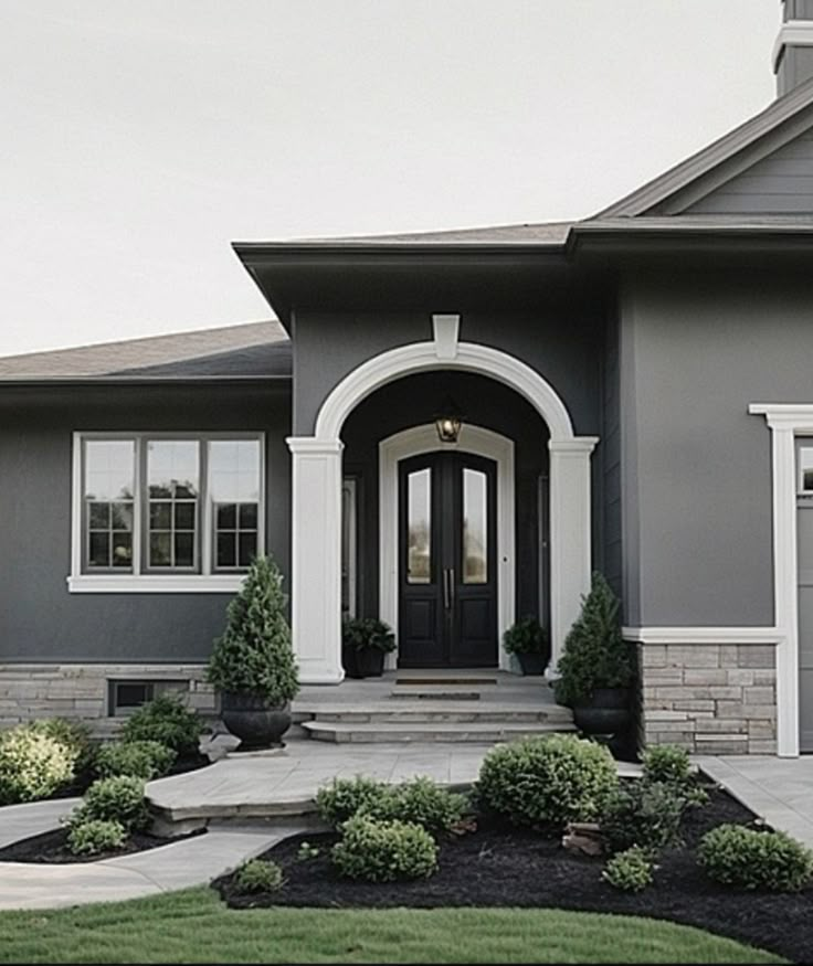 a gray house with white trim and two front doors is shown in the foreground