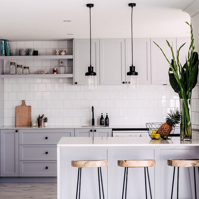 a white kitchen with two stools and an island in front of the countertop