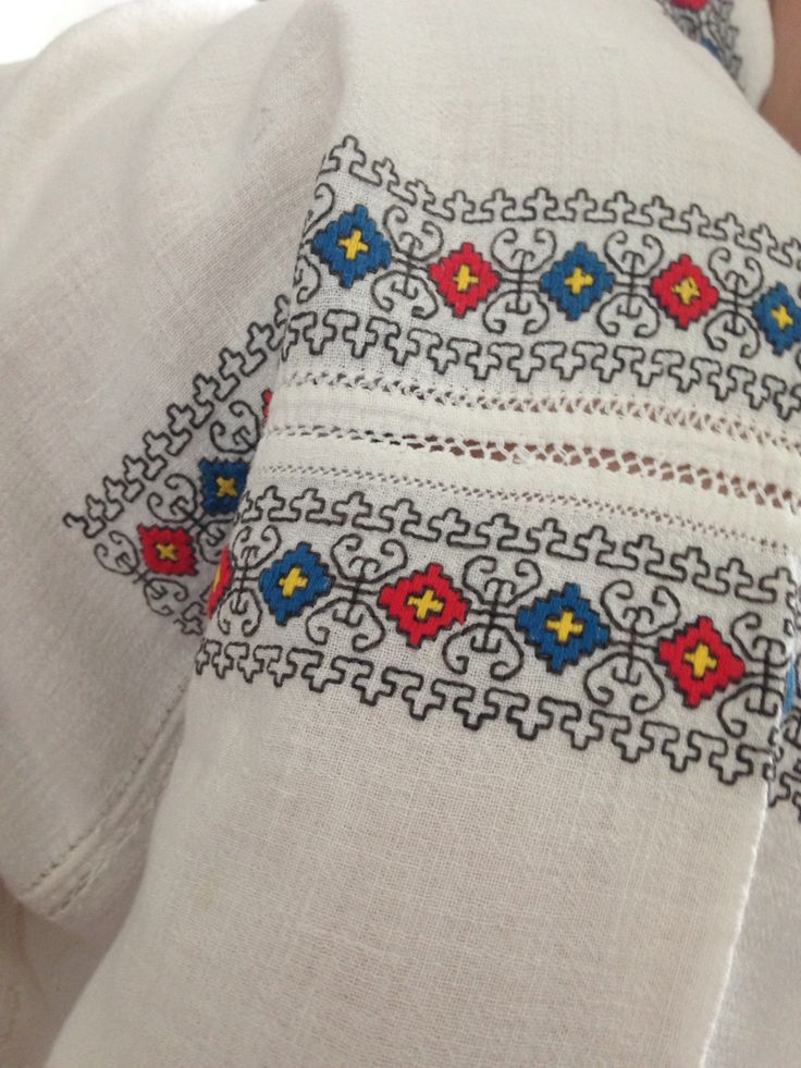 a close up of a person wearing a white shirt with blue, red and yellow designs on it