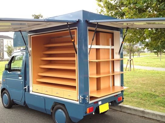 a small blue truck is parked on the side of the road with its doors open