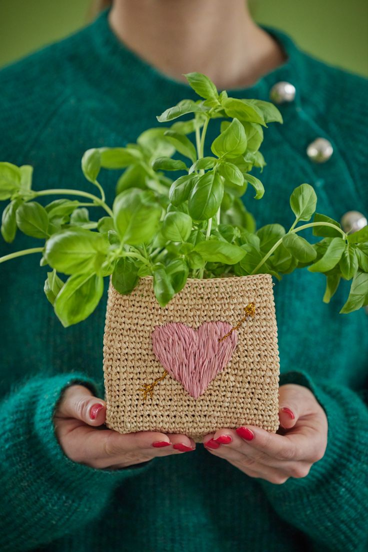 a woman is holding a plant in a burlap bag with a heart drawn on it