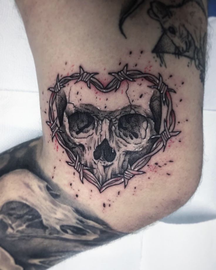 a heart shaped tattoo with two skulls in it