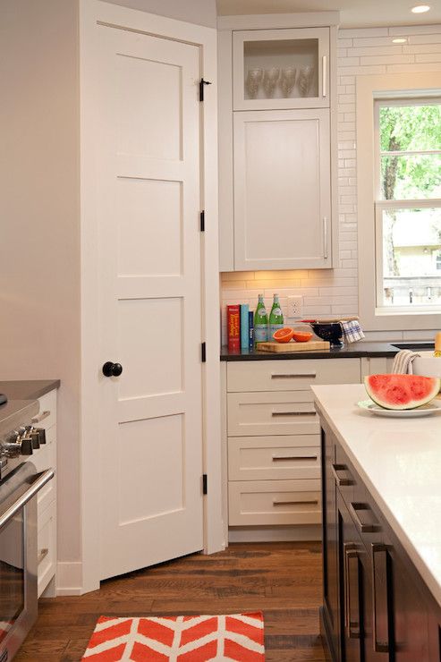 a kitchen with white cabinets and an orange rug