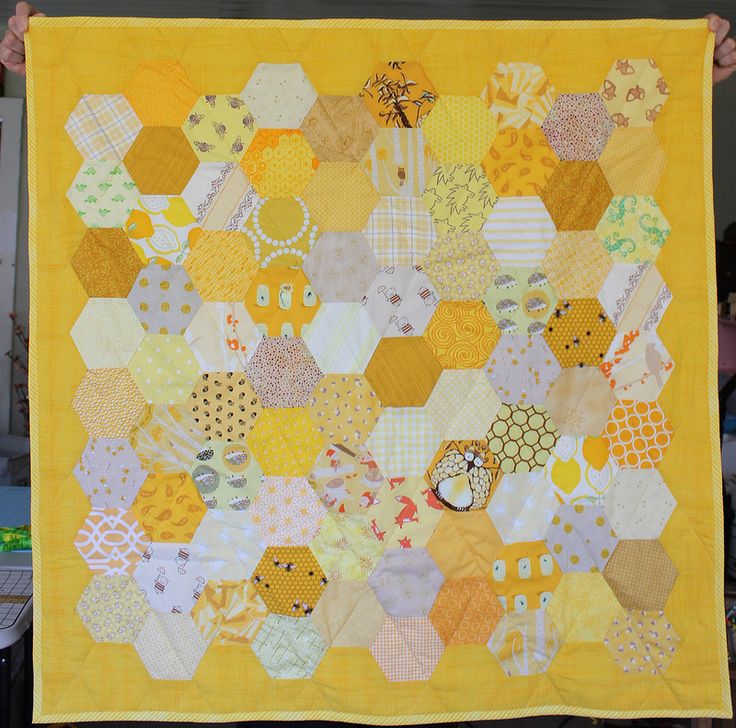 a person holding up a quilt made with hexagons and other small objects