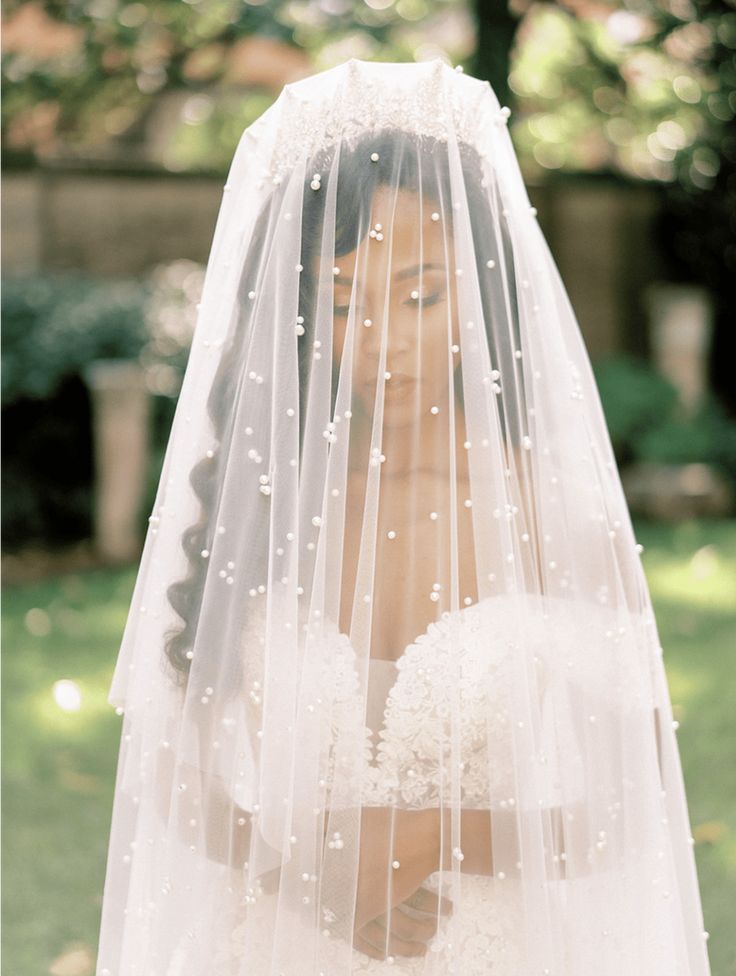 a woman wearing a wedding veil with pearls on it