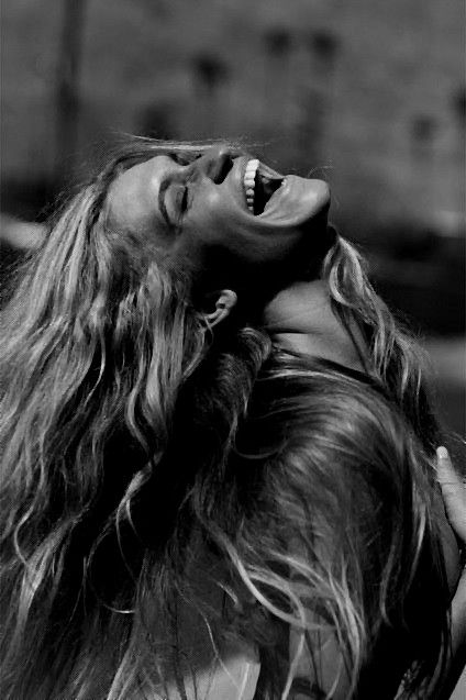 a woman with long hair laughing and looking up