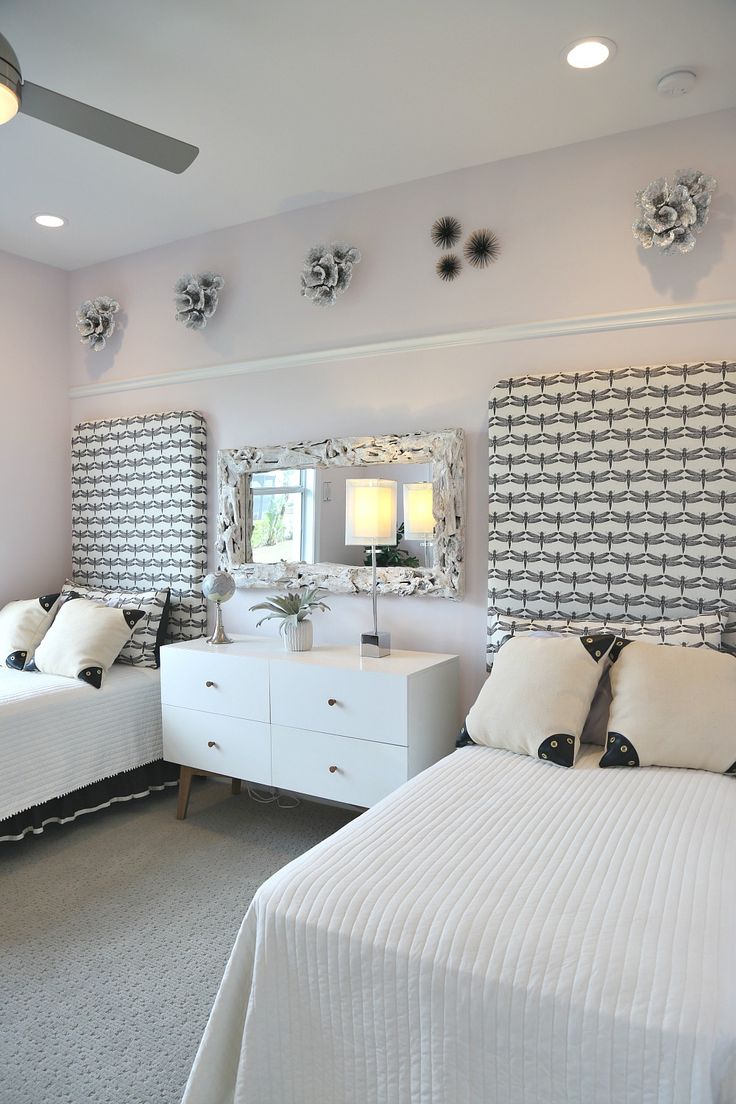 a bedroom with two beds, dressers and mirrors on the wall above them is decorated in black and white