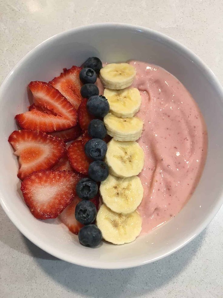 a bowl filled with fruit and yogurt on top of a white countertop